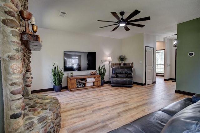 living room featuring visible vents, light wood-style flooring, baseboards, and ceiling fan