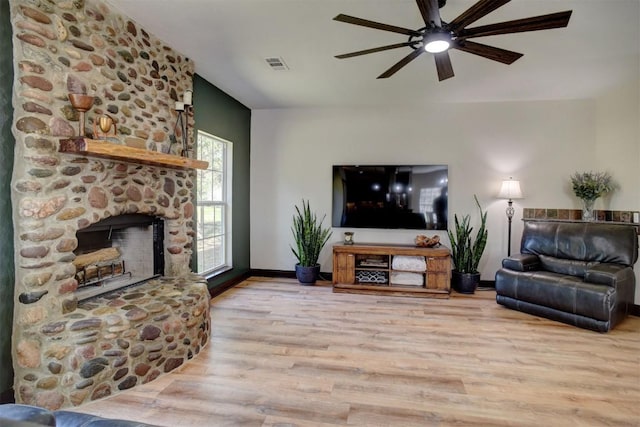 living room with a ceiling fan, baseboards, wood finished floors, visible vents, and a fireplace