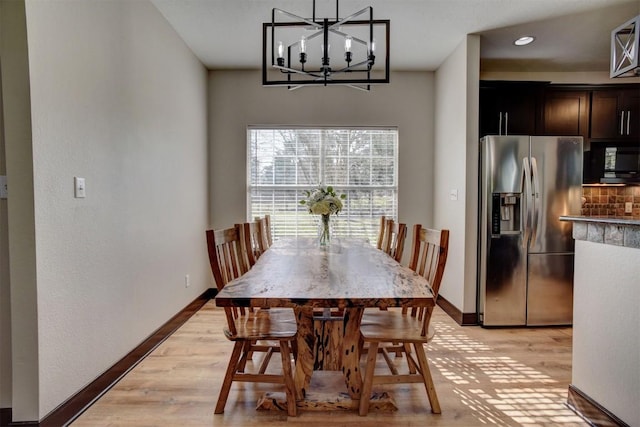 dining area featuring an inviting chandelier, baseboards, and light wood-style floors