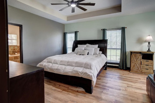 bedroom with ceiling fan, a raised ceiling, and light wood-style floors