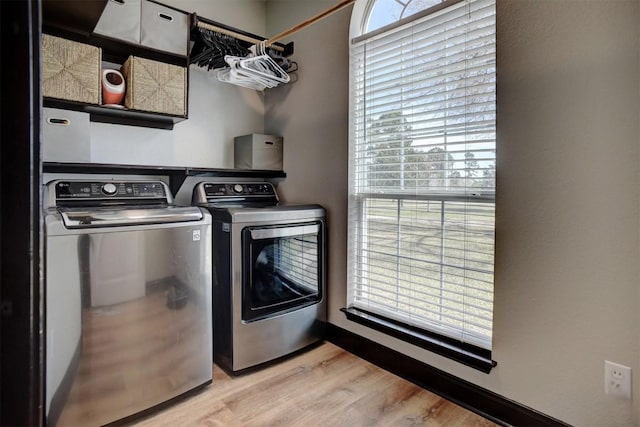 washroom featuring laundry area, washing machine and dryer, and light wood-type flooring