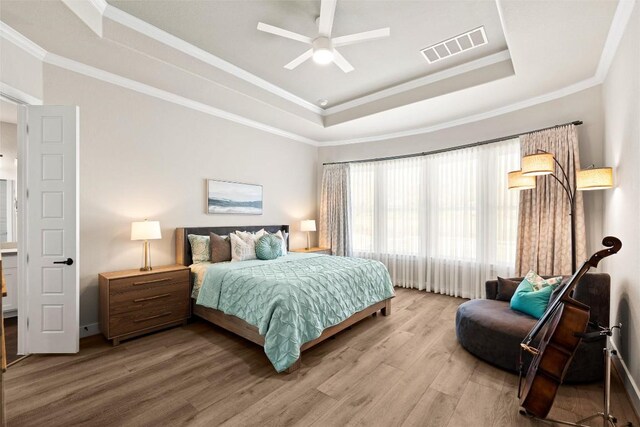 bedroom featuring a tray ceiling, wood finished floors, crown molding, and ceiling fan