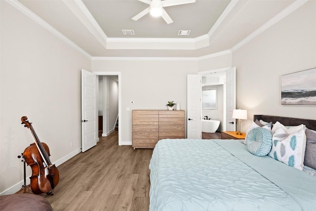 bedroom featuring a tray ceiling, wood finished floors, crown molding, ceiling fan, and baseboards