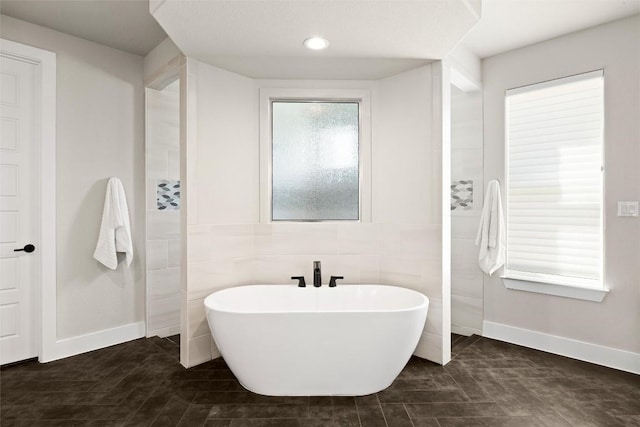 bathroom featuring a freestanding bath and baseboards