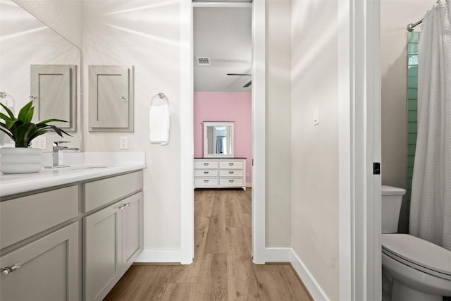 full bathroom with wood finished floors, vanity, baseboards, toilet, and ceiling fan