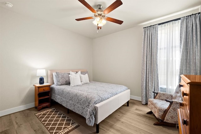 bedroom featuring baseboards, multiple windows, light wood finished floors, and ceiling fan