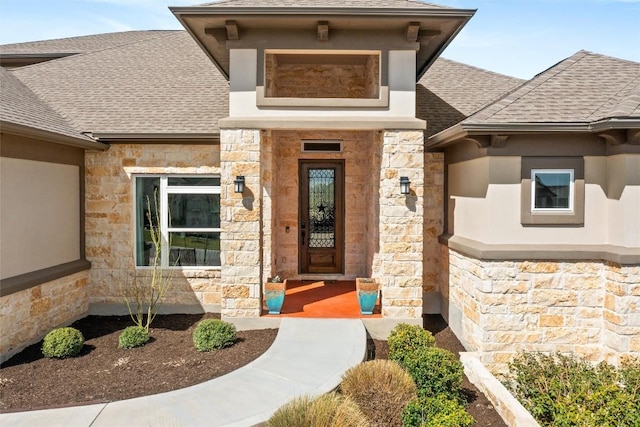 property entrance with stucco siding, stone siding, and a shingled roof