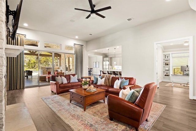 living area featuring visible vents, a stone fireplace, recessed lighting, wood finished floors, and a ceiling fan