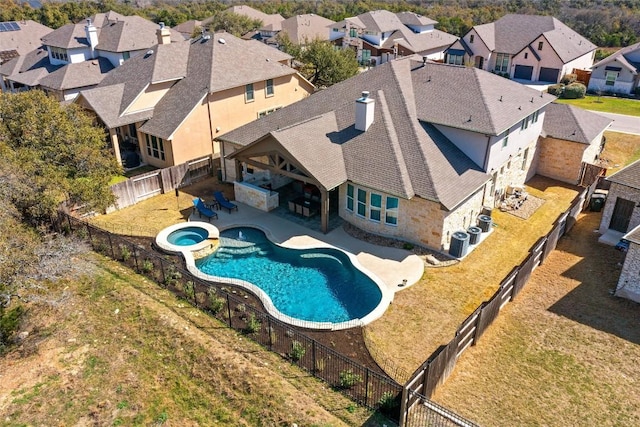 view of pool featuring a pool with connected hot tub, a residential view, a yard, a fenced backyard, and a patio area