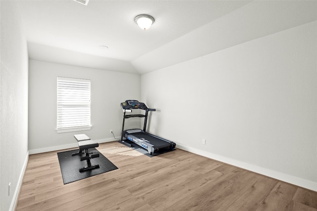 exercise area featuring wood finished floors, baseboards, and lofted ceiling