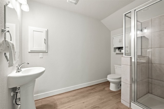 bathroom featuring a stall shower, wood finished floors, toilet, baseboards, and lofted ceiling