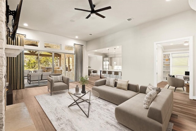 living area with ceiling fan, recessed lighting, wood finished floors, and a fireplace
