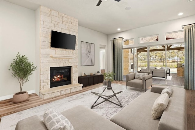 living area with ceiling fan, a stone fireplace, wood finished floors, recessed lighting, and baseboards