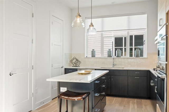 kitchen featuring stainless steel oven, light wood-style floors, and a sink