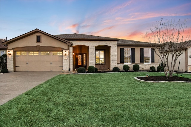 single story home featuring stucco siding, stone siding, a yard, concrete driveway, and a garage