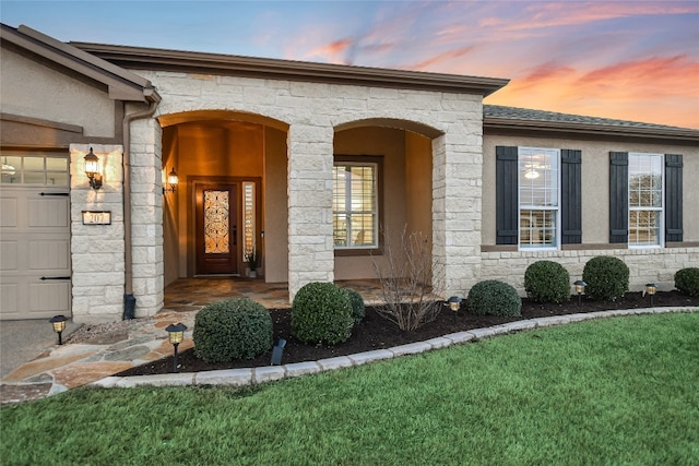 doorway to property featuring a garage, a yard, and stone siding