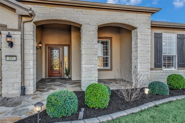 property entrance featuring stucco siding and stone siding