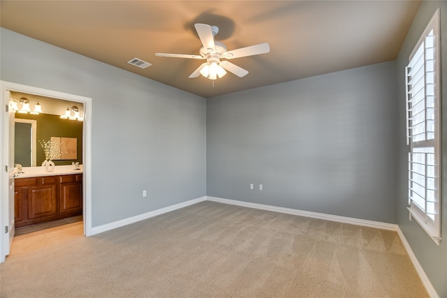 unfurnished bedroom featuring baseboards, light carpet, visible vents, and ensuite bath