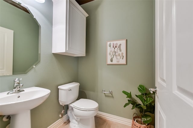 bathroom with tile patterned flooring, toilet, baseboards, and a sink