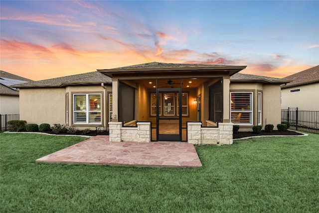 back of property at dusk with a patio, fence, and stucco siding