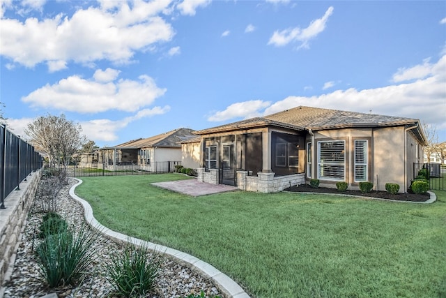 back of house with stucco siding, a lawn, a fenced backyard, and a sunroom