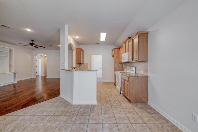 kitchen featuring visible vents, white appliances, arched walkways, light tile patterned floors, and light stone countertops