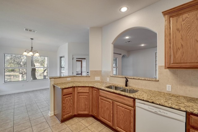 kitchen featuring light stone counters, visible vents, dishwasher, and a sink