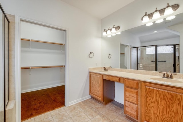 bathroom featuring tile patterned flooring, a stall shower, a walk in closet, and a sink