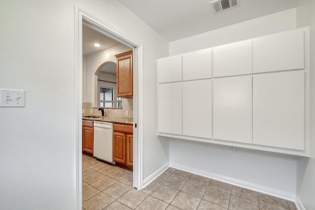 kitchen featuring visible vents, a sink, arched walkways, baseboards, and dishwasher