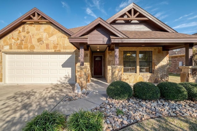 view of front of property with stone siding, concrete driveway, an attached garage, and a shingled roof