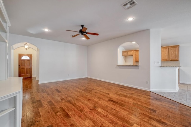 unfurnished living room featuring visible vents, recessed lighting, arched walkways, light wood-style floors, and ceiling fan