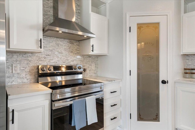 kitchen featuring tasteful backsplash, white cabinets, stainless steel range with electric stovetop, and wall chimney range hood