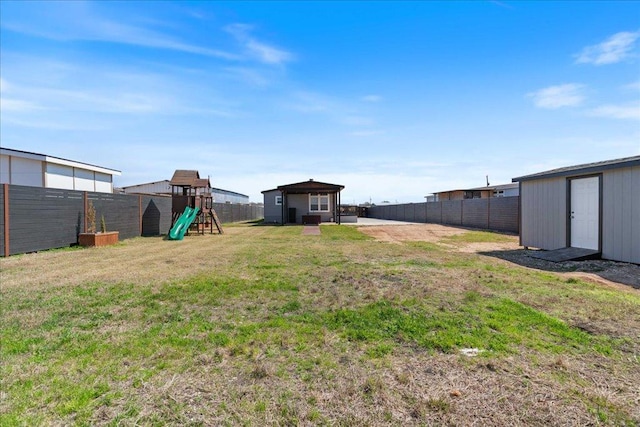 view of yard featuring an outdoor structure, a playground, a fenced backyard, and a shed