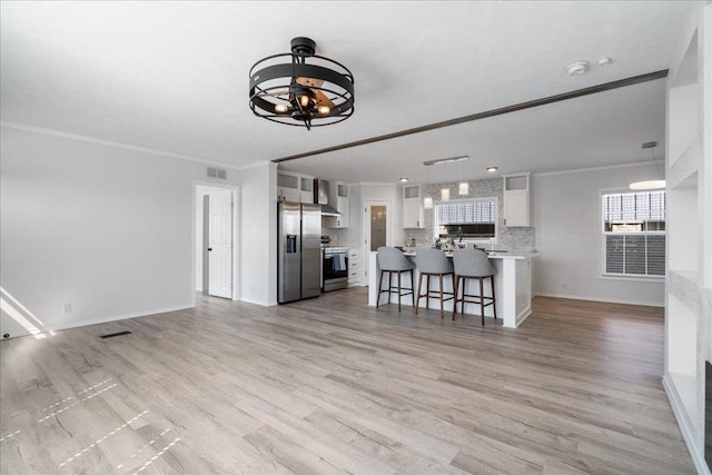 living area featuring crown molding, baseboards, visible vents, and light wood-type flooring