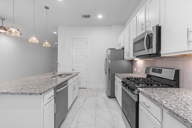 kitchen featuring decorative backsplash, white cabinets, stainless steel appliances, and a sink