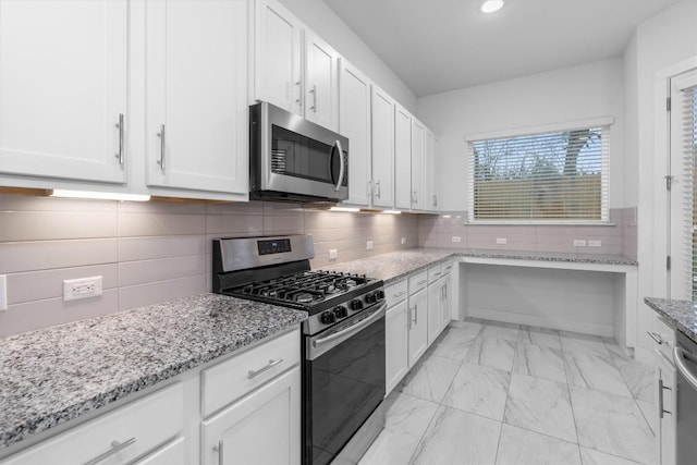 kitchen with marble finish floor, appliances with stainless steel finishes, white cabinets, and light stone countertops