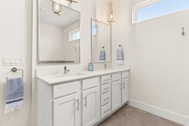 full bath featuring double vanity, tile patterned floors, baseboards, and a sink