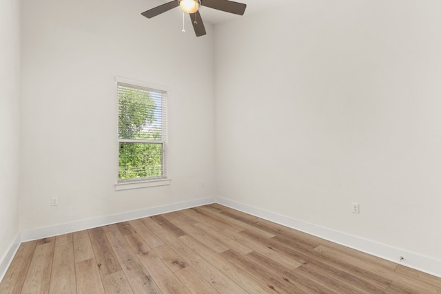 spare room featuring baseboards, light wood-type flooring, and ceiling fan