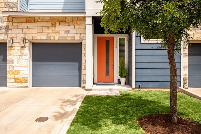 doorway to property featuring stone siding and concrete driveway