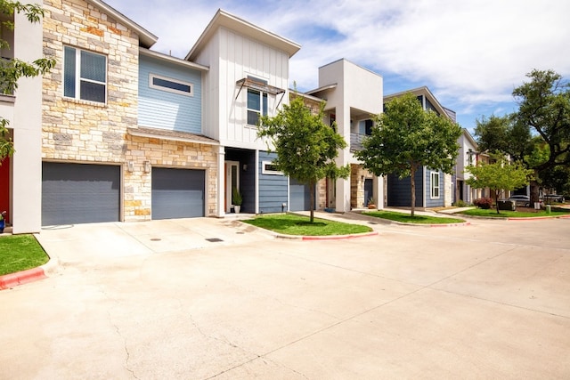 multi unit property featuring stone siding, board and batten siding, concrete driveway, and an attached garage