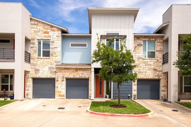 view of front of house with a garage, stone siding, and driveway