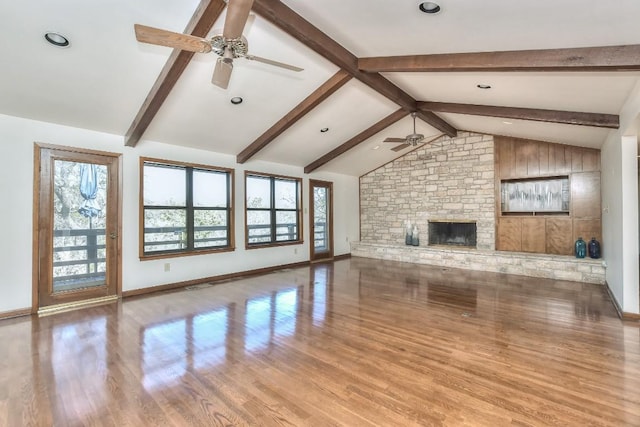 unfurnished living room featuring a wealth of natural light, vaulted ceiling with beams, ceiling fan, and wood finished floors