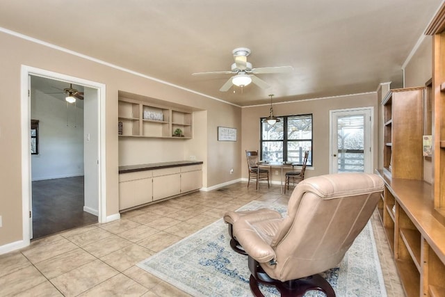 living area featuring light tile patterned floors, baseboards, a ceiling fan, and ornamental molding