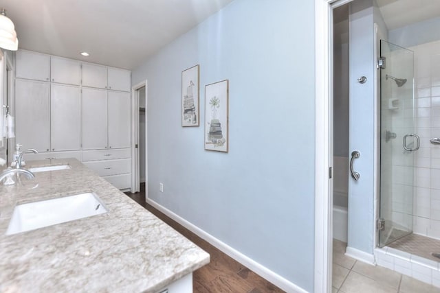 full bath featuring a shower stall, baseboards, and a sink