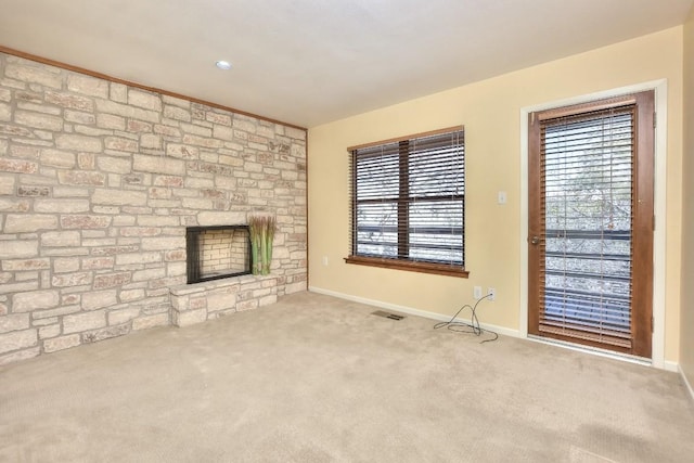 unfurnished living room with a healthy amount of sunlight, visible vents, carpet floors, and baseboards