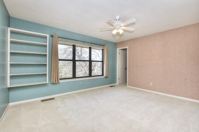 unfurnished bedroom with visible vents, a textured ceiling, carpet flooring, and wallpapered walls