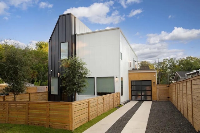 exterior space featuring driveway, a gate, fence, board and batten siding, and a garage