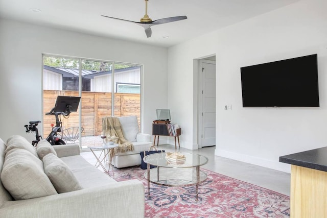 living area with baseboards, finished concrete flooring, and a ceiling fan