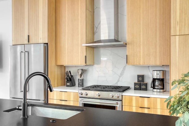 kitchen with a sink, stainless steel appliances, wall chimney range hood, and modern cabinets