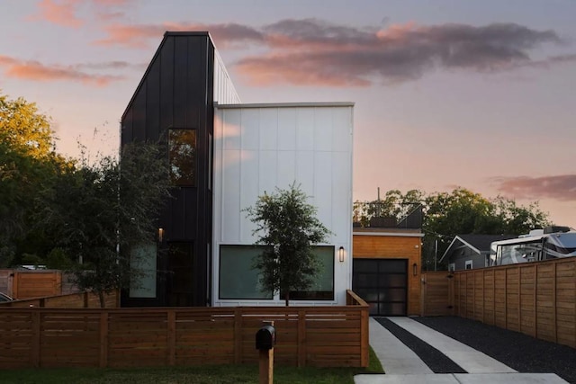 exterior space featuring a gate, fence, board and batten siding, concrete driveway, and an attached garage